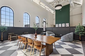 A long wooden table is surrounded by chairs in a room with a checkered floor at LiveWell Apartments, Pittsburgh 15222